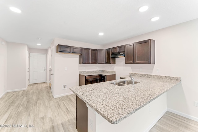 kitchen featuring light hardwood / wood-style flooring, kitchen peninsula, dark brown cabinetry, and sink