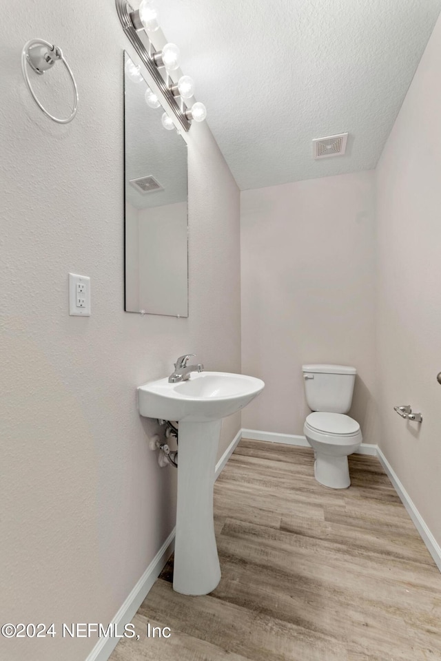 bathroom featuring a textured ceiling, hardwood / wood-style floors, and toilet