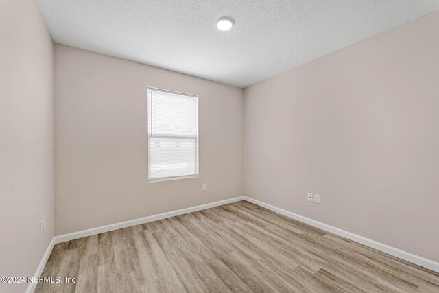 unfurnished room with light hardwood / wood-style floors and a textured ceiling