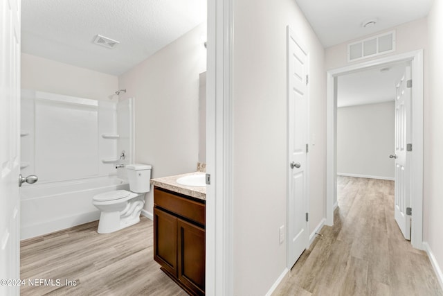 full bathroom featuring vanity, a textured ceiling, toilet, hardwood / wood-style floors, and  shower combination