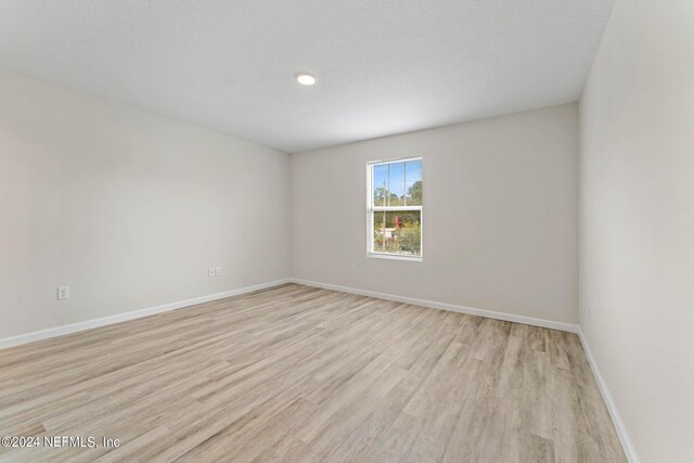 unfurnished room featuring light wood-type flooring and a textured ceiling