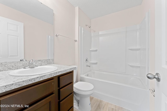 full bath with a textured ceiling, toilet, wood finished floors, vanity, and tub / shower combination