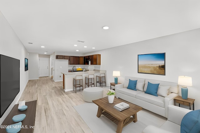 living room with baseboards, light wood-type flooring, visible vents, and recessed lighting