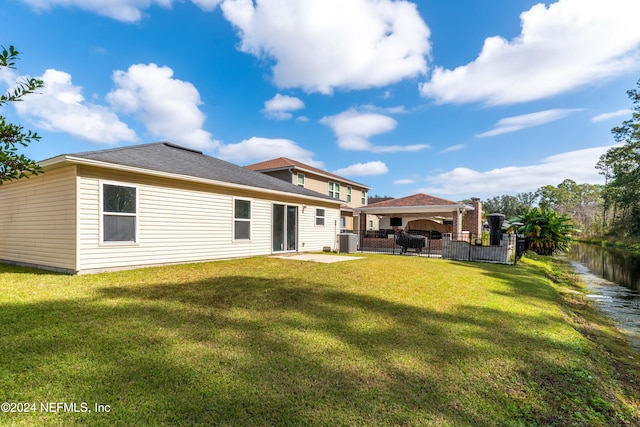 rear view of house featuring cooling unit, a patio area, a water view, and a lawn