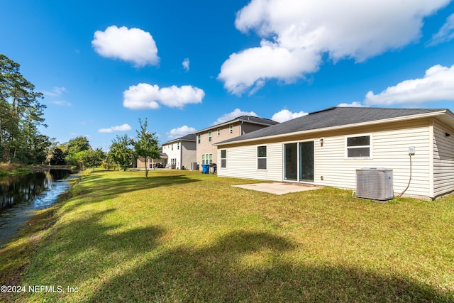 rear view of house featuring a water view, a patio area, central AC, and a lawn