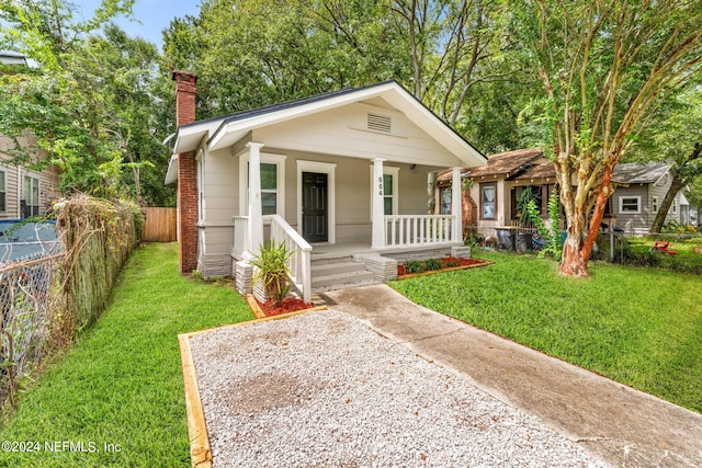 bungalow featuring covered porch and a front yard