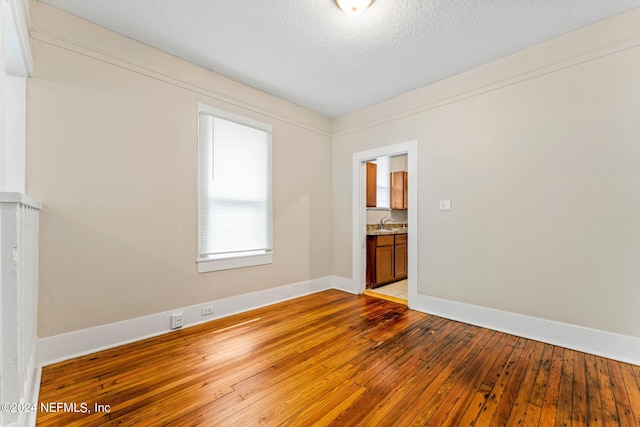 spare room with a textured ceiling and hardwood / wood-style floors