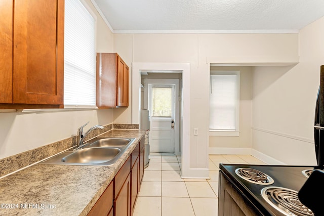 kitchen with a textured ceiling, ornamental molding, sink, and light tile patterned flooring