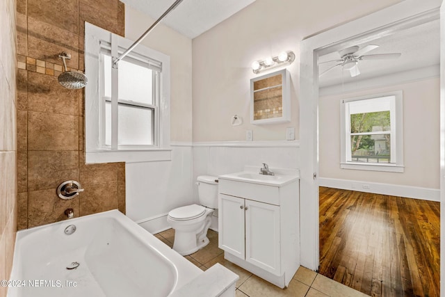 full bathroom with tiled shower / bath, hardwood / wood-style floors, toilet, ceiling fan, and vanity