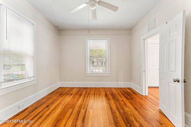 unfurnished room featuring light wood-type flooring, ceiling fan, and a textured ceiling