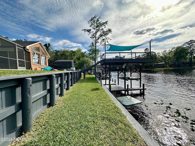 view of dock featuring a water view, boat lift, and a yard