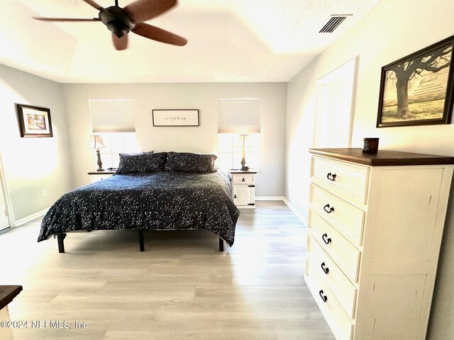 bedroom featuring ceiling fan, wood finished floors, visible vents, and baseboards