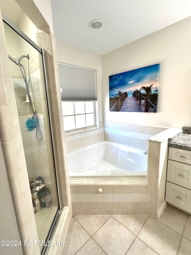 full bathroom with a textured ceiling, a garden tub, vanity, a shower stall, and tile patterned floors