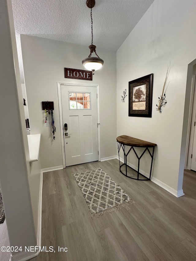 entrance foyer featuring a textured ceiling, baseboards, and wood finished floors