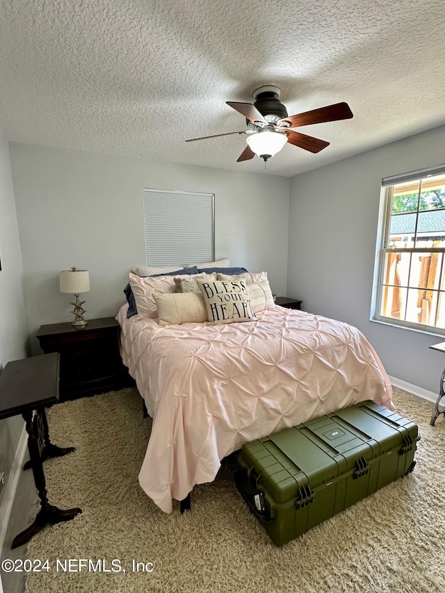 bedroom featuring a ceiling fan, carpet, baseboards, and a textured ceiling