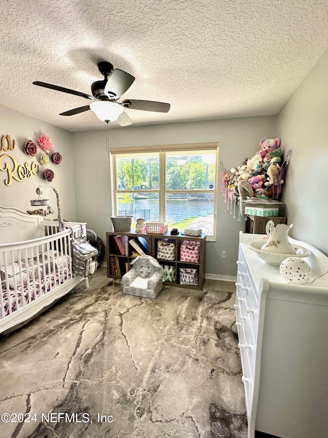 bedroom featuring ceiling fan, a crib, a textured ceiling, and baseboards