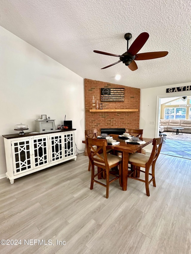 dining space featuring lofted ceiling, ceiling fan, a textured ceiling, and wood finished floors