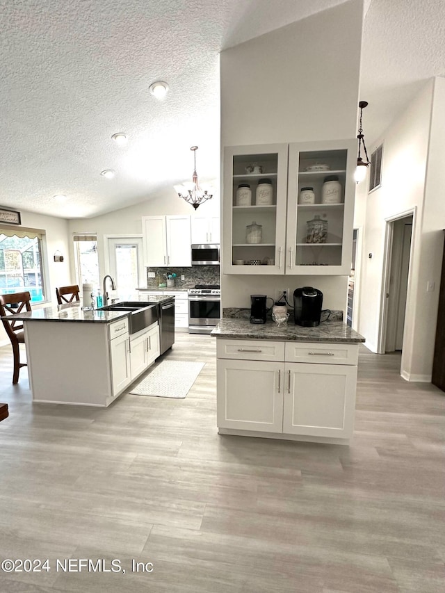 kitchen featuring lofted ceiling, a sink, visible vents, appliances with stainless steel finishes, and light wood finished floors