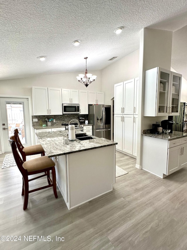 kitchen featuring lofted ceiling, light wood-style floors, light stone counters, and stainless steel appliances