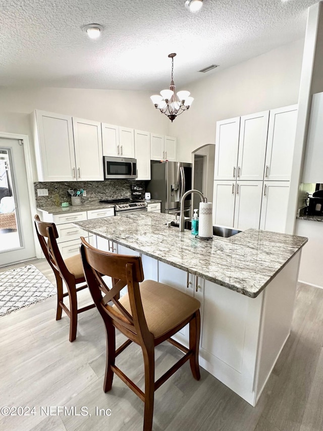 kitchen with light wood-style flooring, vaulted ceiling, stainless steel appliances, and a kitchen breakfast bar