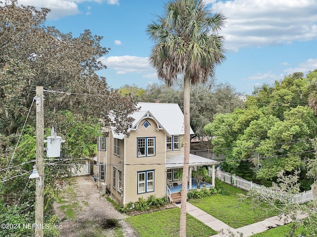 exterior space featuring covered porch, fence, metal roof, driveway, and a front lawn