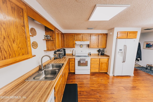 kitchen featuring a textured ceiling, wood-type flooring, sink, and white appliances