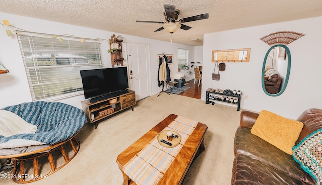 carpeted living area featuring a ceiling fan and a textured ceiling