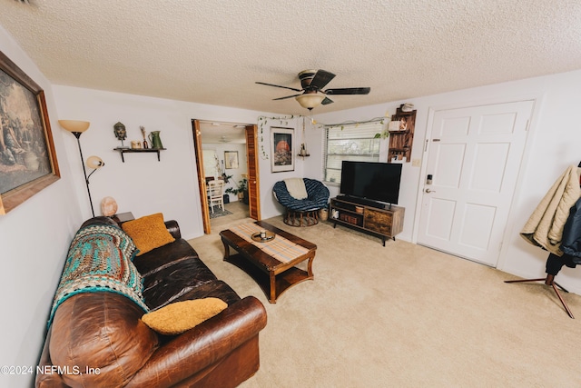 living area featuring carpet, ceiling fan, and a textured ceiling