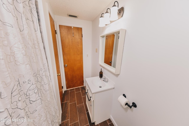 bathroom featuring vanity, visible vents, a textured ceiling, and wood finish floors