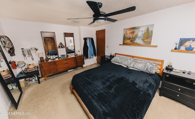 carpeted bedroom featuring ceiling fan and a textured ceiling