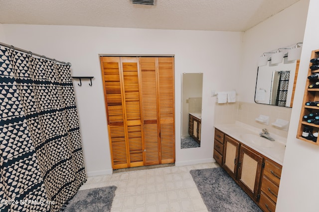 bathroom featuring a textured ceiling, vanity, and backsplash