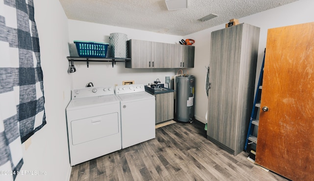 laundry room featuring washing machine and clothes dryer, cabinet space, electric water heater, a textured ceiling, and wood finished floors