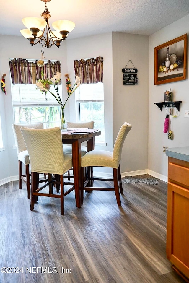 dining area featuring a notable chandelier, dark hardwood / wood-style flooring, and a textured ceiling