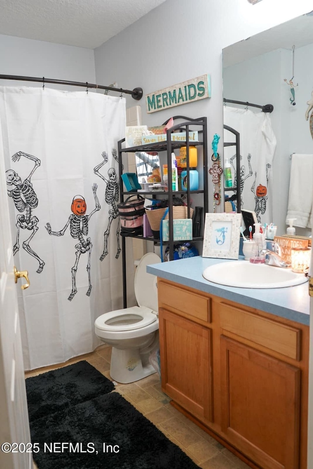 bathroom featuring curtained shower, vanity, a textured ceiling, and toilet