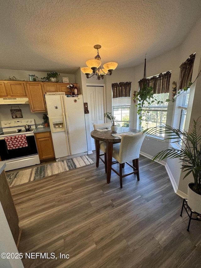 kitchen featuring pendant lighting, white appliances, a textured ceiling, dark hardwood / wood-style flooring, and a chandelier