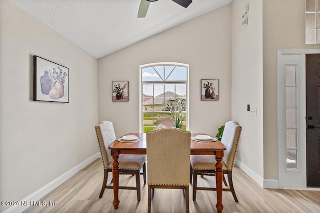 dining space featuring ceiling fan, vaulted ceiling, a textured ceiling, and light hardwood / wood-style flooring