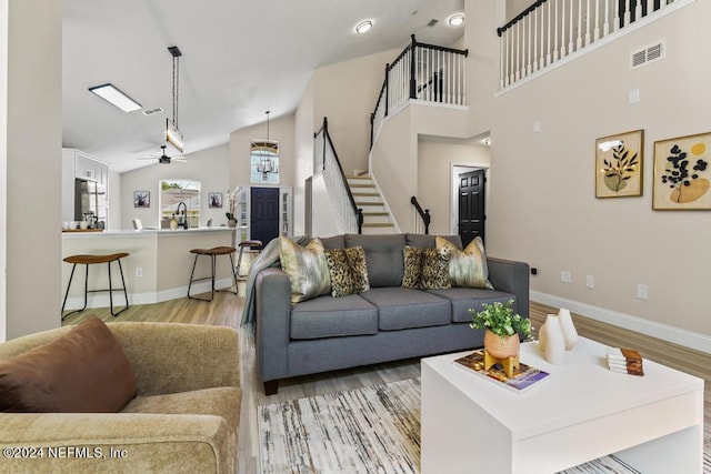 living room with light wood-type flooring, lofted ceiling, sink, and ceiling fan