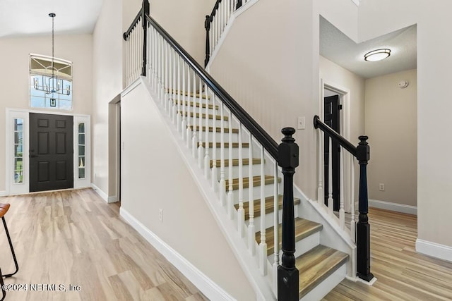 entrance foyer featuring light hardwood / wood-style floors, an inviting chandelier, and a towering ceiling