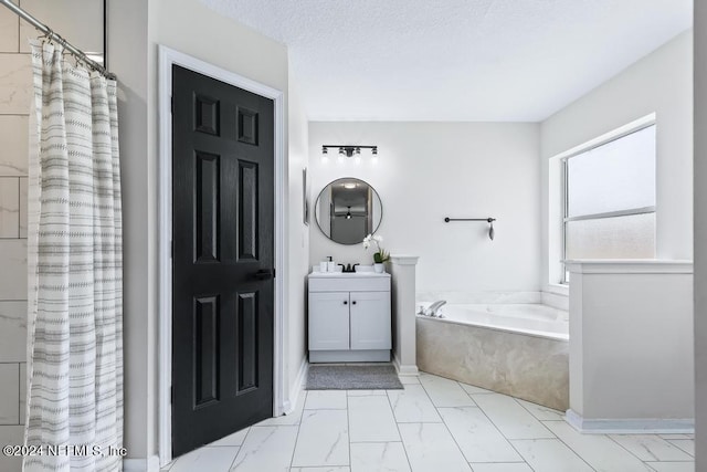 bathroom with a textured ceiling, vanity, and separate shower and tub