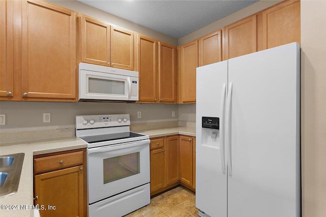 kitchen with white appliances, a textured ceiling, light countertops, and a sink