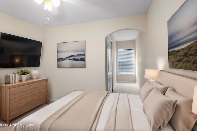 bedroom featuring a ceiling fan, arched walkways, and baseboards