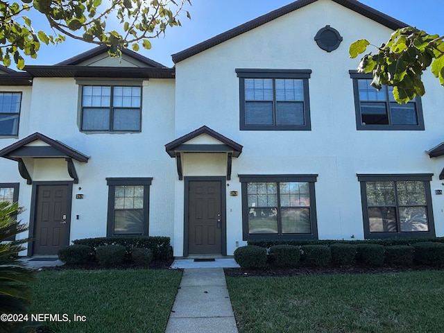 townhome / multi-family property featuring stucco siding and a front yard