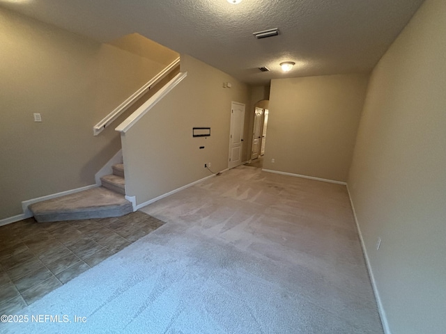 unfurnished living room featuring stairway, baseboards, visible vents, arched walkways, and a textured ceiling