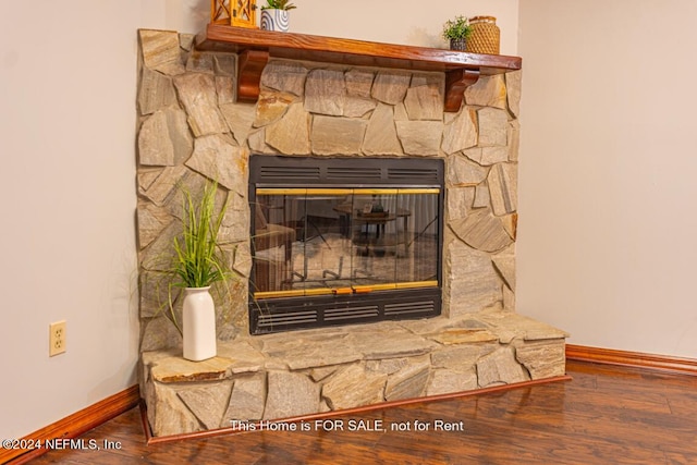 interior details featuring hardwood / wood-style flooring and a stone fireplace