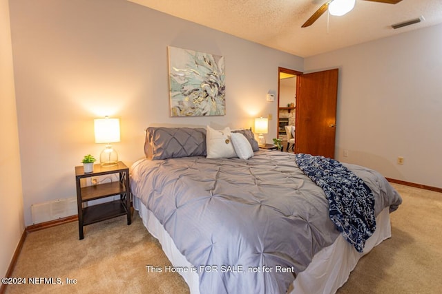 bedroom with ceiling fan, light colored carpet, and a textured ceiling