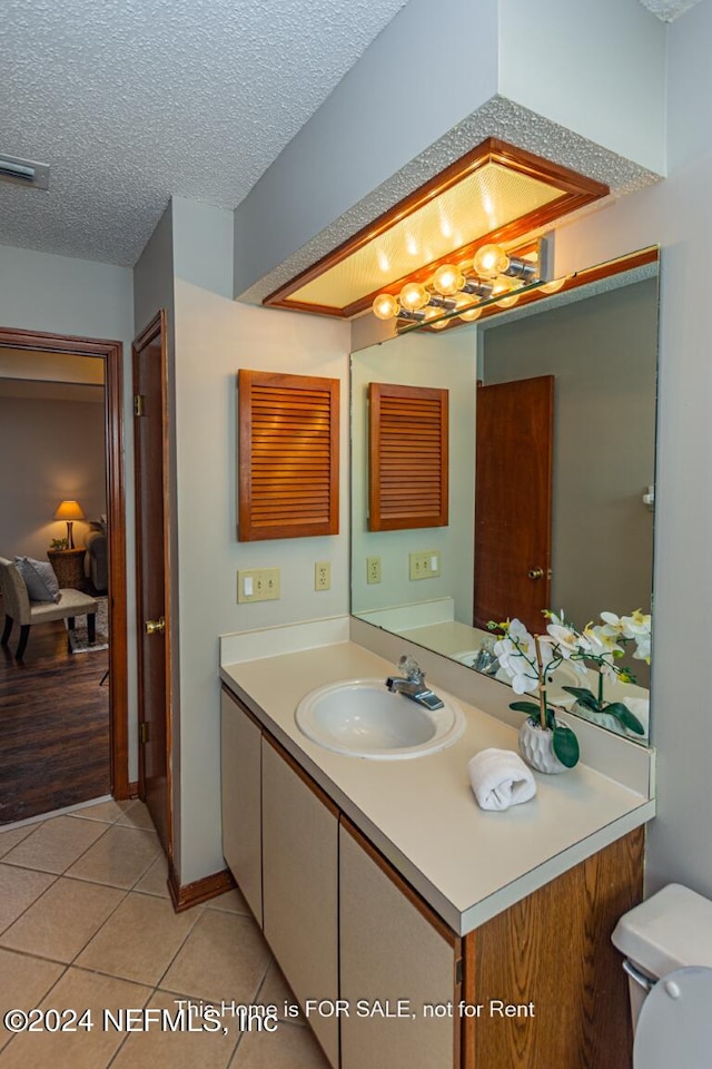 bathroom featuring vanity, tile patterned flooring, toilet, and a textured ceiling