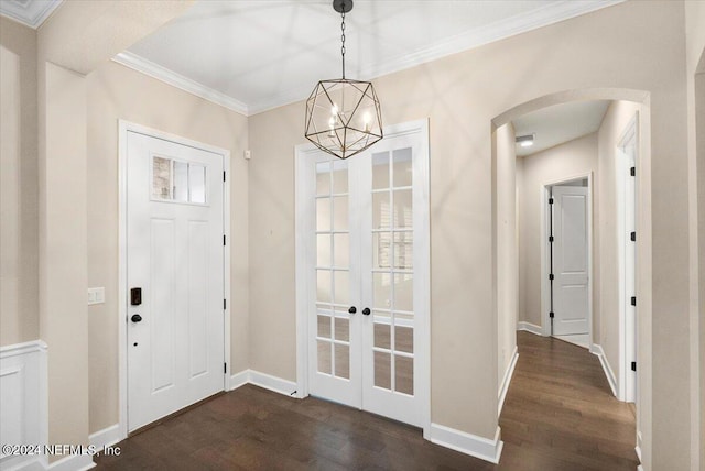 foyer with dark wood-type flooring, crown molding, and a chandelier