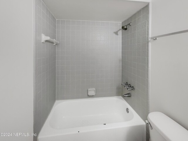 bathroom featuring toilet and tiled shower / bath combo