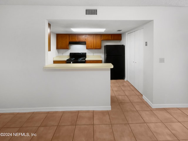 kitchen with black appliances, kitchen peninsula, and light tile patterned flooring