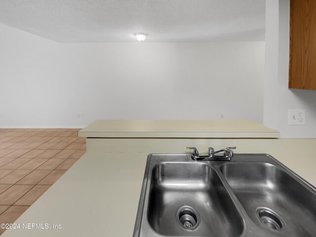 kitchen featuring a textured ceiling, sink, and tile patterned floors